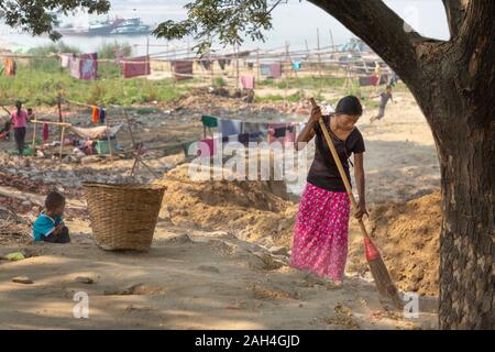 Woman sweeping local dans la colonie près de la rivière Irrawaddy, à Mandalay, Myanmar Banque D'Images