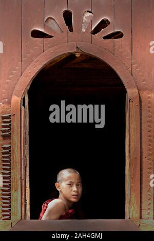 Jeune moine en regardant par la fenêtre du monastère, dans le lac Inle, Myanmar Banque D'Images