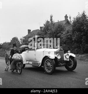 1967, historiques, parade, village anglais, en moto et un vintage Rolls-Royce motor car sur une route, Buckinghamshire, Angleterre. Banque D'Images