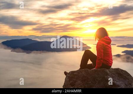 Fille d'aventure au sommet d'une montagne au coucher du soleil Banque D'Images