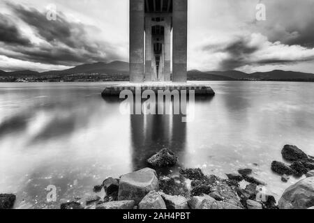 Un contraste élevé noir blanc vue du dessous de la rivière Derwent bridge across Tasman à Hobart au lever du soleil où les nuages reflètent dans l'eau qui dort. Banque D'Images