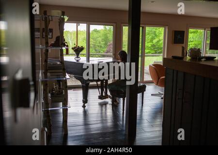 Vue arrière du Teen Girl Playing Piano en Foyer résidentiel Banque D'Images