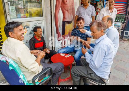 Les hommes jouent aux cartes sur le trottoir : scène de rue à Shahdara district, une banlieue près de l'aéroport de Delhi à New Delhi, capitale de l'Inde Banque D'Images