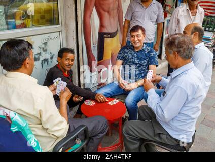 Les hommes jouent aux cartes sur le trottoir : scène de rue à Shahdara district, une banlieue près de l'aéroport de Delhi à New Delhi, capitale de l'Inde Banque D'Images