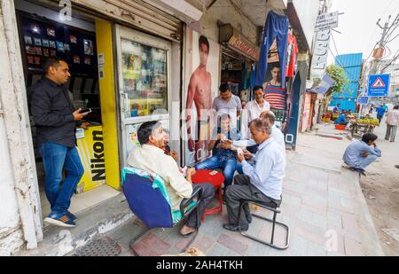 Les hommes jouent aux cartes sur le trottoir : scène de rue à Shahdara district, une banlieue près de l'aéroport de Delhi à New Delhi, capitale de l'Inde Banque D'Images