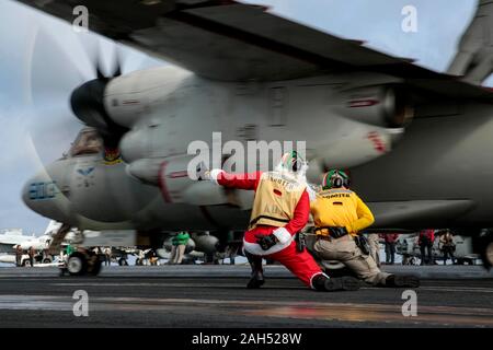 L'USS Abraham Lincoln, États-Unis. 24 Décembre, 2019. Un marin américain habillé en père Noël dirige un avion Hawkeye E-2D dans le poste de pilotage de la classe Nimitz porte-avions USS Abraham Lincoln au cours de l'exploitation la veille de Noël 24 décembre 2019 dans la mer de Chine du Sud. Crédit : Michael Singley/U.S. Navy/Alamy Live News Banque D'Images