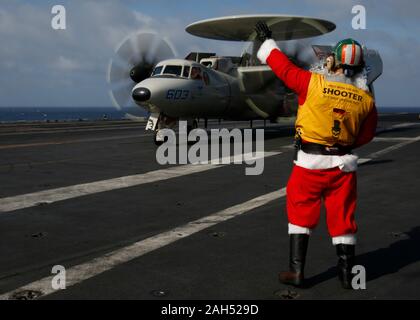 L'USS Abraham Lincoln, États-Unis. 24 Décembre, 2019. Un marin américain habillé en père Noël dirige un avion Hawkeye E-2D dans le poste de pilotage de la classe Nimitz porte-avions USS Abraham Lincoln au cours de l'exploitation la veille de Noël 24 décembre 2019 dans la mer de Chine du Sud. Credit : Ambre Smalley/U.S. Navy/Alamy Live News Banque D'Images