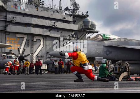 L'USS Abraham Lincoln, États-Unis. 24 Décembre, 2019. Un marin américain habillé en père Noël dirige le lancement d'un F/A-18E Super Hornet dans le poste de pilotage de la classe Nimitz porte-avions USS Abraham Lincoln au cours de l'exploitation la veille de Noël 24 décembre 2019 dans la mer de Chine du Sud. Credit : Jérémie Bartelt/U.S. Navy/Alamy Live News Banque D'Images