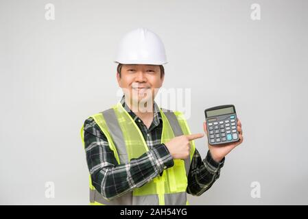 Un homme asiatique d'âge moyen portait un chapeau de travail Combinaison de travail et la tenue d'une calculatrice dans la main. Banque D'Images