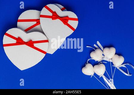 Trois des boîtes en forme de coeur sur un fond bleu. Banque D'Images