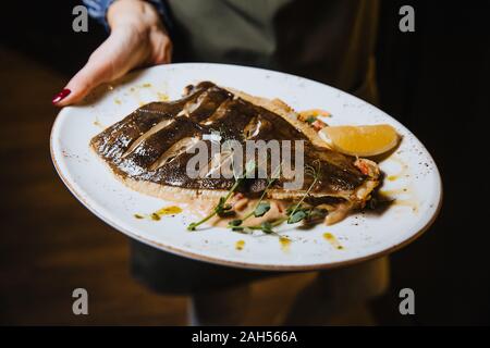 Du poisson cuit au four avec du citron se trouve dans une plaque ronde. Banque D'Images