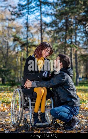 Jeune femme handicapée dans un fauteuil roulant avec copain. L'homme avec jeune fille handicapée dans un fauteuil roulant Banque D'Images