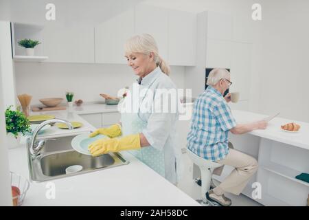 Portrait of cute nice old lady tenir la main, le polissage des plaques de séchage des mains humides profitez de la chambre ont l'intérieur stand kitchenwear Banque D'Images