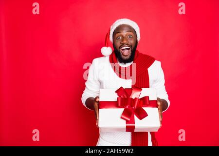 Wow sa pour moi. Portrait d'homme africain excité à santa claus cap tenir gros paquet, se présenter pour nouvel an celebration party de son ami porter st Banque D'Images