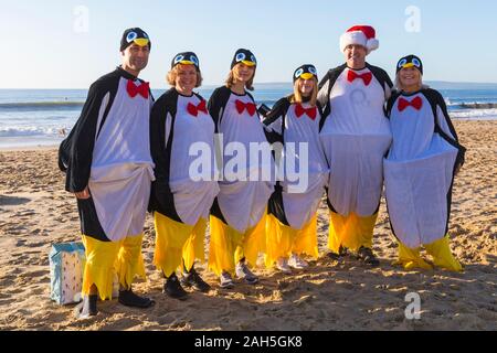 Boscombe, Bournemouth, Dorset, Royaume-Uni. Jour de Noël 25 décembre 2019. Les courageux volontaires plongent dans la mer pour nager ou se baigner lors d'une belle journée ensoleillée, pour l'association caritative annuelle White Christmas DIP, la plus grande trempette de Noël du Royaume-Uni, vêtue de costumes habillés de fantaisie et amassant de l'argent pour Macmillan Caring local à Christchurch, Une unité de soins palliatifs spécialisés pour les patients de la communauté locale. Plus d'un millier prennent part à l'événement qui est devenu une tradition populaire pour beaucoup avant leur déjeuner de Noël. Groupe de pingouins ! Crédit : Carolyn Jenkins/Alay Live News Banque D'Images