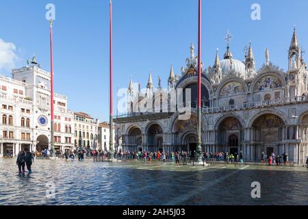 Acqua Alta inondations lors des grandes marées extrêmes de la Piazza San Marco, Venise, Italie avec des gens sur passeroles ou piétonnières près de Basilica San Marco Banque D'Images