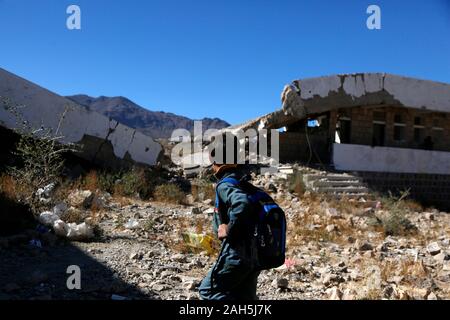 (191225) -- IBB, 25 décembre 2019 (Xinhua) -- un étudiant promenades dans le Shuhada-Alwahdah Al-Radhmah dans le district scolaire de la province d'Ibb, Yémen, le 23 décembre 2019. La guerre au Yémen a forcé plus de deux millions d'enfants de l'école et de mettre 3,7 millions d'autres personnes à haut risque en raison du non-paiement des salaires des enseignants, en fonction de l'Organisation des Nations Unies pour l'enfance (UNICEF). Mais pour ceux qui peuvent revenir, ils vont tout tenter pour revenir à la classe, même de s'asseoir sur les décombres d'airstrike touchés les écoles. Pour aller avec 'Caractéristique : les étudiants yéménites retour à l'airstrike-hit school' (photo de M Banque D'Images