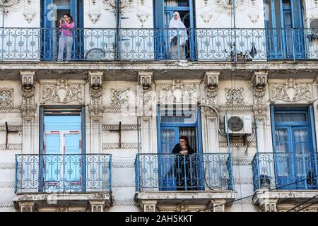 Alger, Algérie. Dec 25, 2019. Les femmes sont dans les balcons d'un immeuble résidentiel à regarder les funérailles du Chef d'état-major de l'armée algérienne Ahmed Gaid Salah, qui est décédée lundi à l'âge de 79 ans suite à une crise cardiaque. Salah, l'un des principaux acteurs dans une année difficile pour l'Algérie, a été considéré comme déterminant dans la démission du président Abdelaziz Bouteflika en avril, ajoutant à la pression sur la barre après des protestations de masse dans le pays. Credit : Farouk Batiche/dpa/Alamy Live News Banque D'Images