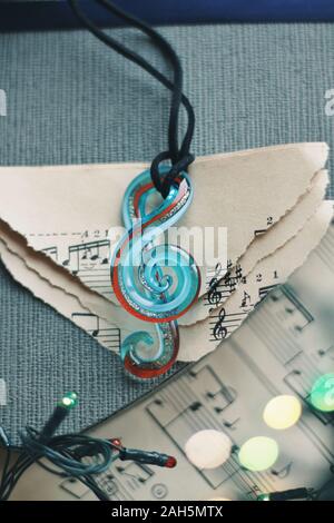 De la jeunesse et de la musique romantique. Composition de bijoux sur fond intérieur avec bokeh. Chaînette comme note musicale, clé de verre pour cadeau, mariage, nouveau Oui Banque D'Images