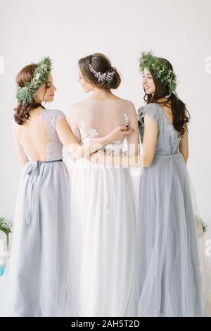 Bride standing avec son dos dans une robe de mariée blanche avec deux demoiselles en robe bleue. Banque D'Images