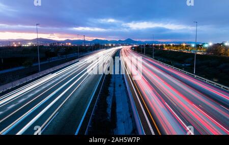 L'autoroute au coucher du soleil, les véhicules roulant dans les deux sens de la lumière, des sentiers laissant revenir à la maison du travail Banque D'Images