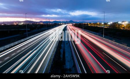 L'autoroute au coucher du soleil, les véhicules roulant dans les deux sens de la lumière, des sentiers laissant revenir à la maison du travail Banque D'Images