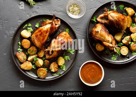 Les carcasses de cailles grillées savoureuses avec des pommes sur fond noir en noir. Cailles rôties sur plaque. Haut de la vue, télévision lay Banque D'Images