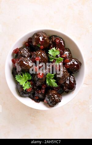 Boulettes de viande avec sauce aux canneberges dans un bol blanc sur fond noir en lumière. Ragoût de boulettes de viande en sauce aux baies sucrées. Haut de la vue, télévision lay Banque D'Images