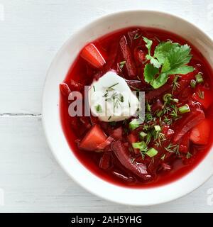 Close up of Russian soup (bortsch) avec les verts et la crème sure. Soupe de betteraves dans un bol blanc sur fond de bois. Haut de la vue, télévision lay Banque D'Images