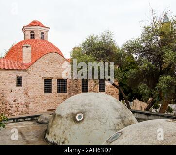 Vieux bâtiment en brique avec un toit rouge parmi les arbres verdoyants. Journée ensoleillée. Antalya, Turquie, le 6 avril 2019. Banque D'Images