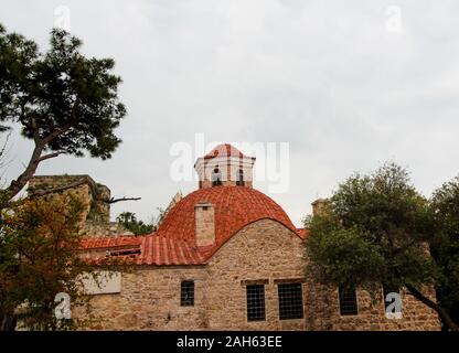 Vieux bâtiment en brique avec un toit rouge parmi les arbres verdoyants. Journée ensoleillée. Antalya, Turquie, le 6 avril 2019. Banque D'Images