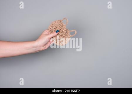 Eco débarbouillettes tricotées pour laver la vaisselle sur un fond gris dans a woman's hand Banque D'Images