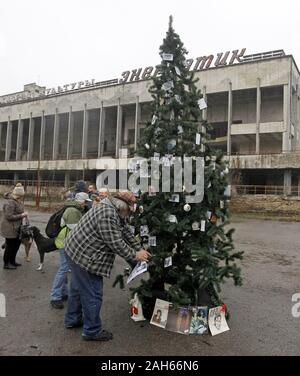 Kiev, Ukraine. Dec 25, 2019. Les anciens habitants de Pripyat décorer avec leurs photos d'un arbre de Noël installé sur une place centrale de la ville abandonnée Pripyat, environ 3 km de la centrale nucléaire de Tchernobyl, l'Ukraine, le 25 décembre 2019.Les anciens habitants de Pripyat, certains n'ont pas voir leur ville pour plus de 33 ans, venaient de Slavutych à Pripyat pour décorer l'arbre de Noël avec des photos de famille prises dans Pripyat avant expulsion. L'action visant à attirer l'attention sur la préservation de la ville de Pripyat et d'autres structures et des objets de la zone d'exclusion de Tchernobyl. Le Cher Banque D'Images
