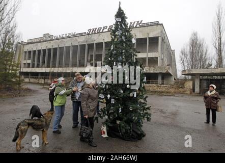 Kiev, Ukraine. Dec 25, 2019. Les anciens habitants de Pripyat décorer avec leurs photos d'un arbre de Noël installé sur une place centrale de la ville abandonnée Pripyat, environ 3 km de la centrale nucléaire de Tchernobyl, l'Ukraine, le 25 décembre 2019.Les anciens habitants de Pripyat, certains n'ont pas voir leur ville pour plus de 33 ans, venaient de Slavutych à Pripyat pour décorer l'arbre de Noël avec des photos de famille prises dans Pripyat avant expulsion. L'action visant à attirer l'attention sur la préservation de la ville de Pripyat et d'autres structures et des objets de la zone d'exclusion de Tchernobyl. Le Cher Banque D'Images