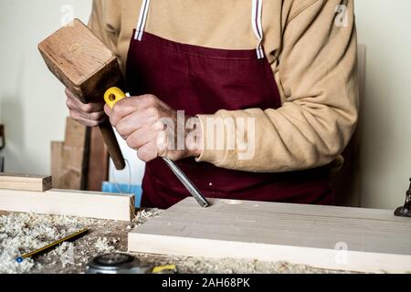 Les mains du charpentier avec un burin sur le banc de travail du bois Banque D'Images