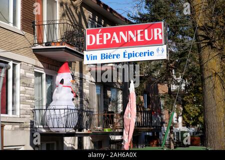 Dépanneur Montréal sign 'Dépanneur- Vin Biere' sur une journée ensoleillée avec bonhomme de neige gonflable sur balcon Banque D'Images