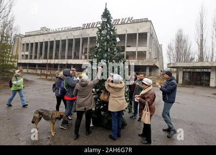 Les anciens résidents de la Pripyat décorer un arbre de Noël qui a été installé sur la place centrale de la ville fantôme de Pripyat, près de la centrale nucléaire de Tchernobyl avec des photos de famille.La dernière fois qu'un arbre de Noël a été installé à Pripyat en décembre 1985. 18 Les anciens résidents de Pripyat, certains qui n'ont pas vu leur ville pour plus de 33 ans, est venu à la ville abandonnée de décorer un arbre de Noël avec leurs photos de famille qui ont été pris dans la ville avant de Pripyat a été évacué. L'objectif de l'action est la préservation, l'museuming et la protection des objets de la zone d'exclusion de Tchernobyl, dans Banque D'Images