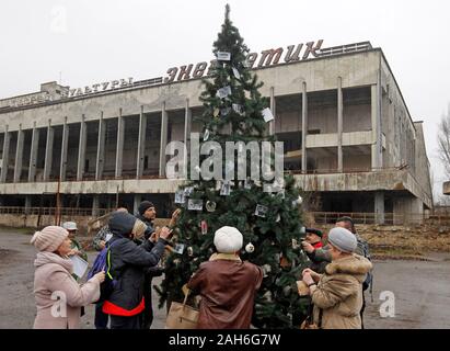 Les anciens résidents de la Pripyat décorer un arbre de Noël qui a été installé sur la place centrale de la ville fantôme de Pripyat, près de la centrale nucléaire de Tchernobyl avec des photos de famille.La dernière fois qu'un arbre de Noël a été installé à Pripyat en décembre 1985. 18 Les anciens résidents de Pripyat, certains qui n'ont pas vu leur ville pour plus de 33 ans, est venu à la ville abandonnée de décorer un arbre de Noël avec leurs photos de famille qui ont été pris dans la ville avant de Pripyat a été évacué. L'objectif de l'action est la préservation, l'museuming et la protection des objets de la zone d'exclusion de Tchernobyl, dans Banque D'Images