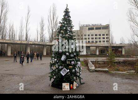 Les anciens résidents de la Pripyat décorer un arbre de Noël qui a été installé sur la place centrale de la ville fantôme de Pripyat, près de la centrale nucléaire de Tchernobyl avec des photos de famille.La dernière fois qu'un arbre de Noël a été installé à Pripyat en décembre 1985. 18 Les anciens résidents de Pripyat, certains qui n'ont pas vu leur ville pour plus de 33 ans, est venu à la ville abandonnée de décorer un arbre de Noël avec leurs photos de famille qui ont été pris dans la ville avant de Pripyat a été évacué. L'objectif de l'action est la préservation, l'museuming et la protection des objets de la zone d'exclusion de Tchernobyl, dans Banque D'Images