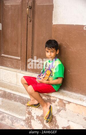 Les gens de La Havane - un jeune garçon, assis sur la porte s'abaisser devant sa maison. Banque D'Images