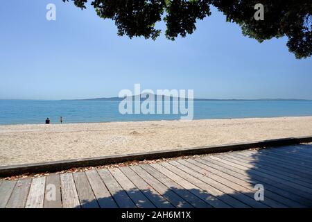 Une mère et d'enfant en profiter du soleil et de la vue de l'île de Rangitoto de St Heliers Beach, Auckland, Nouvelle-Zélande Banque D'Images