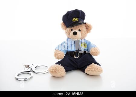 L'arrestation de la police et de concept. Mignon ours en agent de police menottes et uniforme contre isolé sur fond blanc Banque D'Images