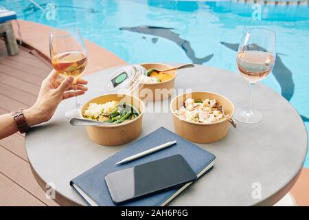 Trois des plats sains emballées dans des boîtes en carton sur cafe de table avec verre de vin rose Banque D'Images