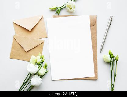 Maquette carte blanche et de l'artisanat avec eustoma enveloppes. Invitation de mariage dans un style minimaliste avec eustoma. Banque D'Images