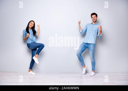 Corps plein photo de Guy et lady célébrant nouveau projet d'affaires soulevant des poings, jean décontracté vêtements couleur de fond gris isolé Banque D'Images