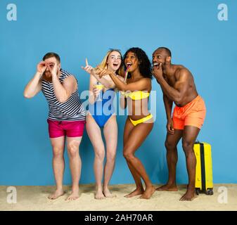 Prêts à faire la fête. Heureux les jeunes amis se reposer et s'amuser sur fond studio bleu. Concept d'émotions humaines, expression du visage, vacances d'été ou de fin de semaine. Chill, été, mer, océan. Banque D'Images