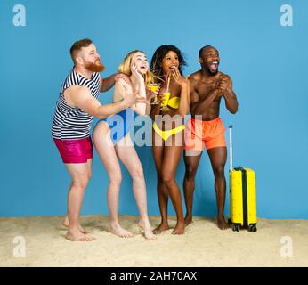 Prêts à faire la fête. Heureux les jeunes amis se reposer et s'amuser sur fond studio bleu. Concept d'émotions humaines, expression du visage, vacances d'été ou de fin de semaine. Chill, été, mer, océan. Banque D'Images