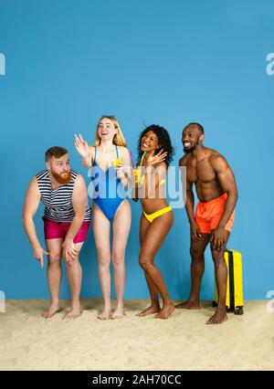 Prêts à faire la fête. Heureux les jeunes amis se reposer et s'amuser sur fond studio bleu. Concept d'émotions humaines, expression du visage, vacances d'été ou de fin de semaine. Chill, été, mer, océan. Banque D'Images