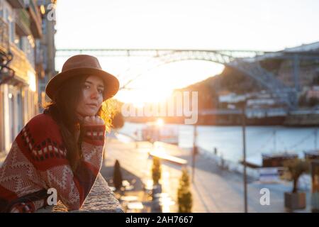 Les gens, les voyages, vacances et d'aventure concept. Jeune femme aux cheveux longs walking on city street au lever du soleil, porter un chapeau et manteau, appréciant heureux ple Banque D'Images