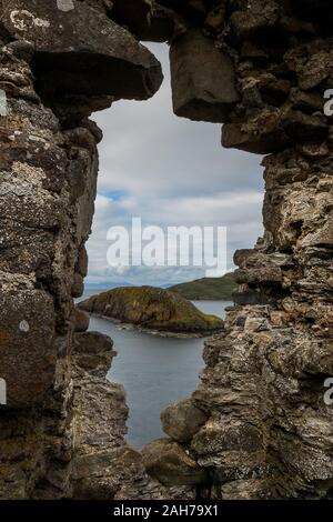 Par une ouverture sur un mur de roche peut être vu la mer et une petite île Banque D'Images